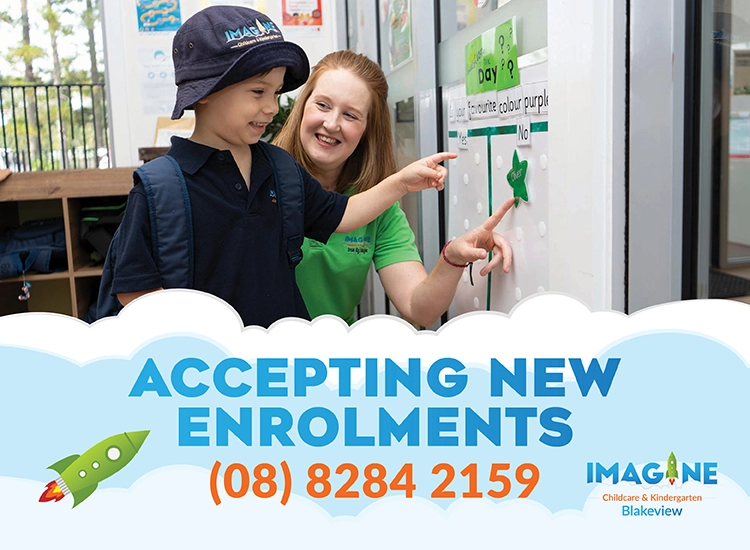 Teacher guides a child pointing at a display about accepting new enrolments; shows phone number and center logo.